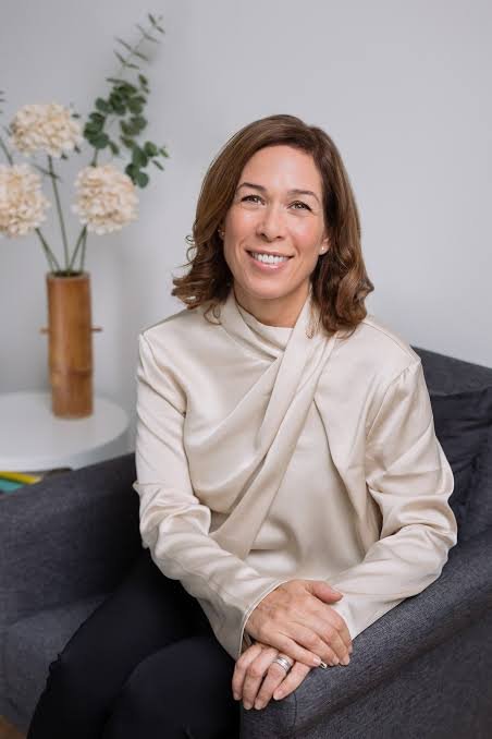 Portrait of the therapist smiling, seated in a warmly lit therapy room